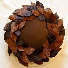 a chocolate cake decorated with leaves on a plate