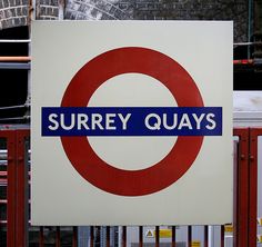 there is a sign that says surrey quays in blue and red on the front