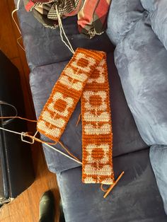 two crocheted scarfs sitting on top of a blue couch