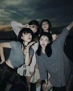 four young women posing for the camera with their arms in the air and one holding her head