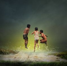 three boys jumping into the water with their arms around each other in front of them