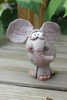 an elephant figurine with eyes and ears on it's head sitting on a wooden floor