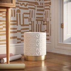 a white vase sitting on top of a wooden floor next to a wallpapered wall