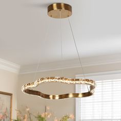 a modern chandelier hanging from the ceiling in a dining room with flowers on the table