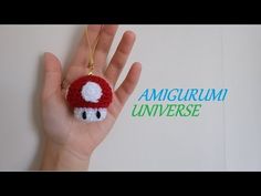 a hand holding a small red mushroom ornament in it's palm with the words amigurum universe written on it