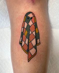 a tattoo on the leg of a person with an orange and green scarf around it