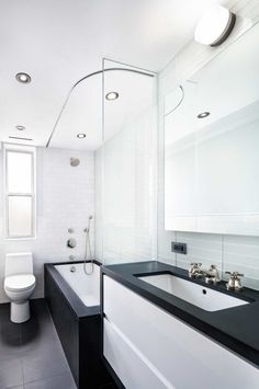 a black and white bathroom with a tub, sink, toilet and shower head mounted to the wall