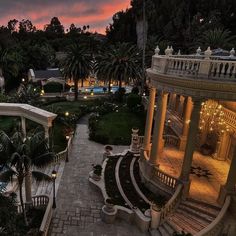 an aerial view of a mansion at dusk with palm trees and lights in the foreground