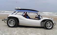 a white car parked on top of a sandy beach