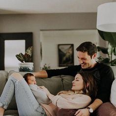 a man and woman sitting on a couch with a baby