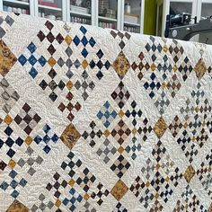 an old quilt is on display in a room with many bookshelves behind it