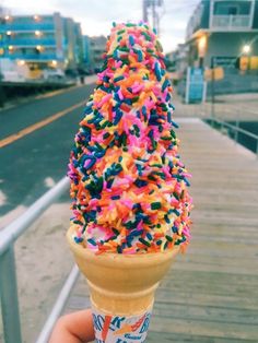 an ice cream cone filled with sprinkles on top of a wooden deck