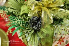 a christmas centerpiece with pine cones and green ribbons