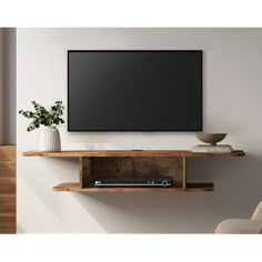 a flat screen tv mounted to the side of a wooden shelf next to a plant