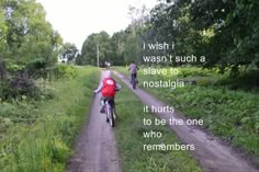 two bicyclists riding down a dirt road with a quote on the back