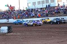 several cars are racing on dirt in front of an audience