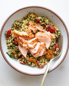 a white bowl filled with rice and meat on top of a table next to a fork