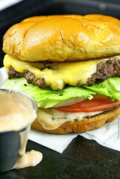 a cheeseburger with lettuce, tomato and sauce on the side is ready to be eaten