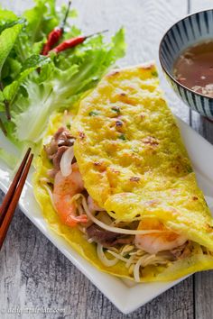 an omelet on a plate with chopsticks next to it and the words vietnamese sizzling crepes