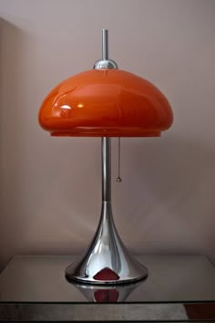 an orange lamp sitting on top of a glass table