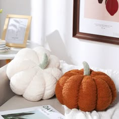 two pumpkins sitting on top of a bed next to a magazine and framed photograph