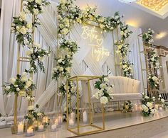 a wedding stage decorated with white flowers and greenery, candles and gold stands on the floor