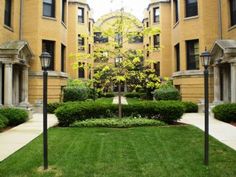 an apartment building with trees and bushes in the front yard