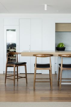 two wooden chairs sitting at a table in a kitchen with white cabinets and wood floors