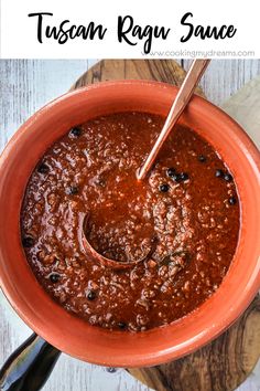 an orange bowl filled with chili sauce on top of a wooden cutting board next to a spoon