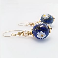 Experience the exquisite craftsmanship of Italian artisans with our Blue Round Millefiori Earrings. These stunning earrings feature white floral designs on gold-filled wires, showcasing Venetian beads measuring 14 mm in diameter that are expertly crafted with murano glass. Gold-filledearring wires Hypoallergenic 14 mm diameter Made-in-Italy Venetian beads Gift packaging is included Each Murano bead is made individually Murano beads made by talented craftsmen in Italy Genuine Austrian crystals Statement earring Made in the USA NOTE Each Murano bead is handmade individually, making each one unique. This is not considered a flaw but rather adds to the distinctiveness of the jewelry. RETURNS AND EXCHANGES We offer a 100% satisfaction guarantee. We want you to be happy with our beaded jewelry. Crystal Statement Earrings, Murano Glass Jewelry, Earring Wires, Gold Filled Earrings, Venetian Glass, Seed Bead Necklace, Wire Bracelet, Stunning Earrings, Bead Earrings