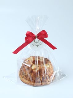 a bag of cookies wrapped in plastic with a red ribbon around it on a white background