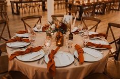 the table is set with white plates and silverware, orange napkins, and candles