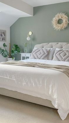 a white bed sitting in a bedroom next to a window with a wreath on the wall