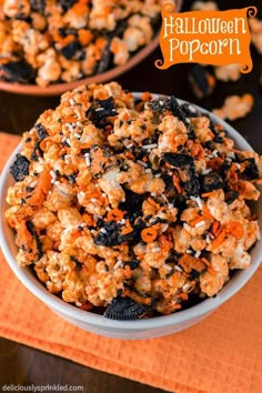 a bowl filled with halloween popcorn sitting on top of a table next to an orange napkin