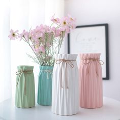 three vases with flowers in them sitting on a table