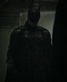 the dark knight is standing in the rain