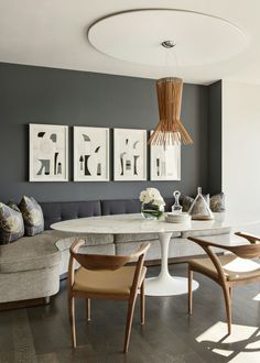 a modern dining room with grey walls and white furniture, including an oval table surrounded by chairs