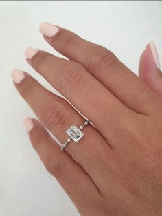 a woman's hand with a diamond ring on her left hand, and a white background