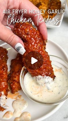 a person dipping sauce onto chicken tenders on a plate