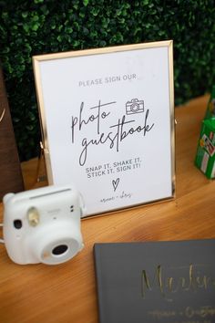 there is a sign that says photo guestbook next to a camera and other items on the table