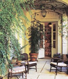 an outdoor patio with wicker chairs and potted plants on either side of the door