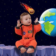 a little boy in an orange astronaut suit sitting on a ledge next to the earth