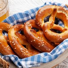 several pretzels in a basket next to a glass of beer