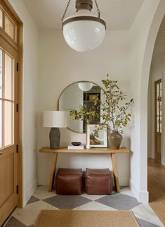 a hallway with a mirror, lamp and vase on the table in front of it