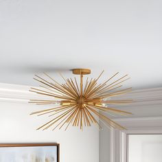 a gold chandelier hanging from the ceiling in a living room with white walls