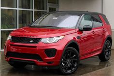 a red land rover parked in front of a building