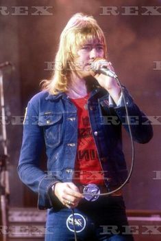 an image of a man singing into a microphone at a music festival in the 80s