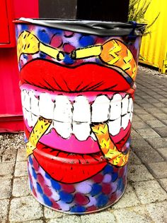 a painted trash can with teeth and tongues on it