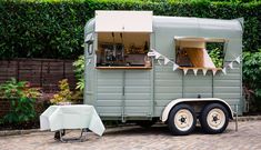 a food truck parked in front of a brick wall with tables and chairs around it