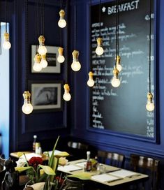 a dining room with blue walls and lights hanging from the ceiling